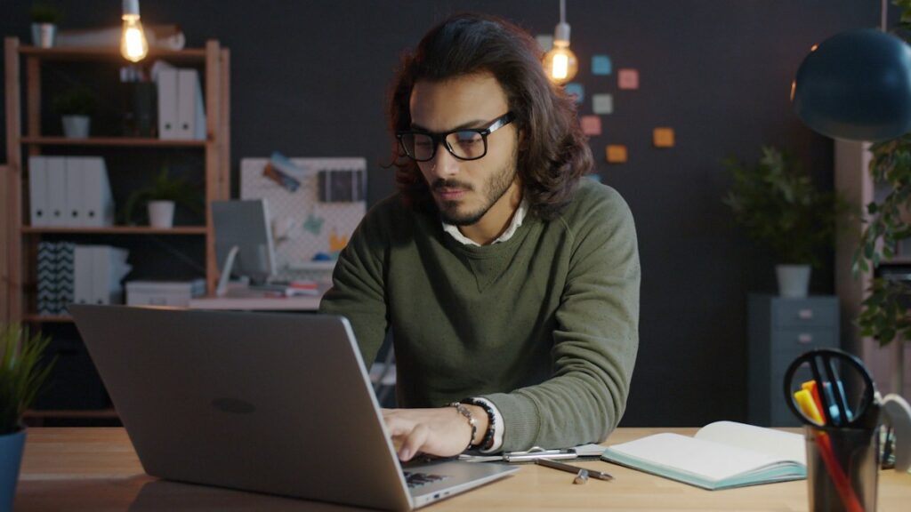 Man in glasses working on resume bullet points on a laptop