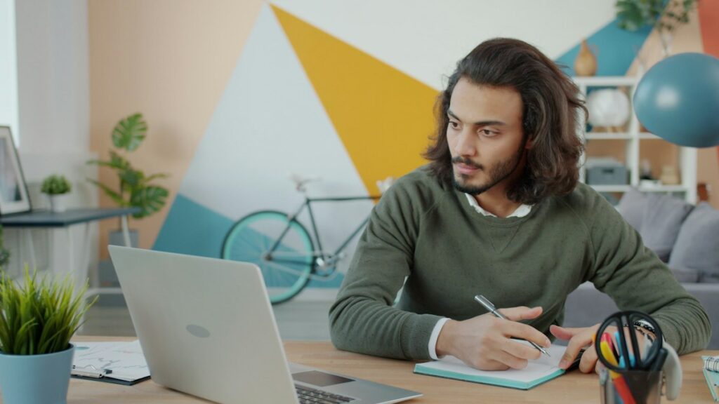 Job seeker taking notes while using AI to rewrite resume bullets