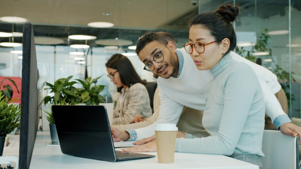 Two colleagues comparing CV formats on a laptop