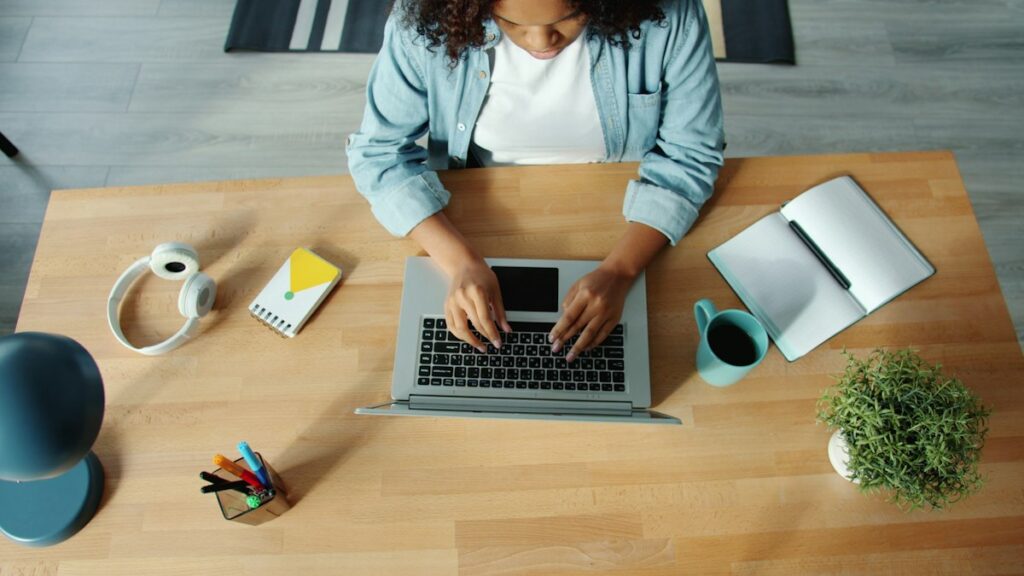 Top view of a woman typing her resume on a laptop at home